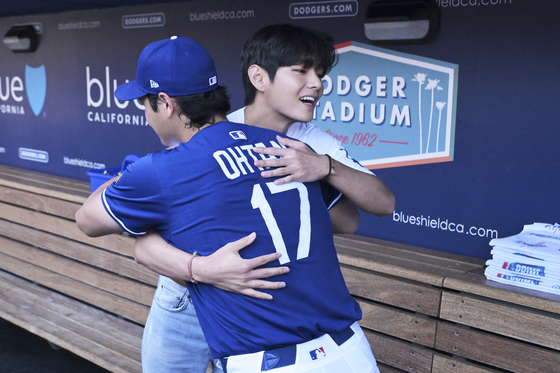 그룹 방탄소년단(BTS)의 뷔가 25일(현지시간) 미국 프로야구 메이저리그(MLB) 로스앤젤레스(LA) 다저스의 홈경기 시구에 앞서 다저스 소속 스타선수 오타니 쇼헤이와 만나 포옹하고 있다. AP=연합뉴스