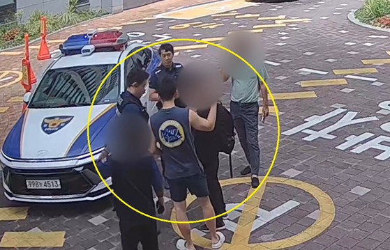 대전서부경찰서 형사과 이진웅 경사가 휴가 중 보이스피싱 현금수거책을 검거한 뒤 출동한 경찰관에게 범인을 인계하고 있다. [사진 대전경찰청]