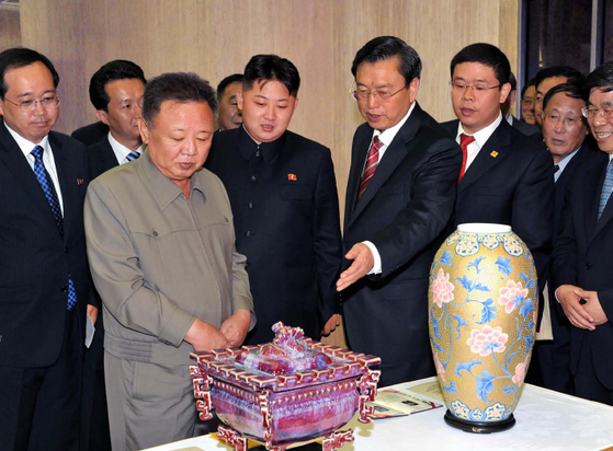 2011년 7월 김정일과 앳된 얼굴의 김정은 국무위원장이 평양을 방문한 장더장(張德江) 중국 부총리를 단장으로 하는 중국 친선대표단이 준 선물을 바라보는 모습. 북한 선전용 웹사이트 캡처, 연합뉴스