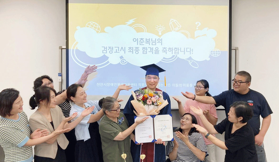 고졸 검정고시에 합격한 이춘복씨(가운데)가 천안시장애인평생교육센터 관계자들로부터 축하 인사를 받고 있다. [사진 천안시]