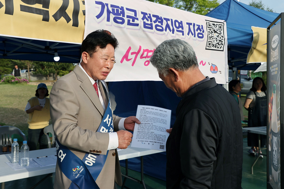 서태원 가평군수(왼쪽)가 지난해 4월 22일부터 6월 말까지 실시한 ‘가평군 접경지역 지정 범군민 서명운동’에서 한 주민으로부터 접경지역 지정을 촉구하는 서명을 받고 있다. 사진 가평군