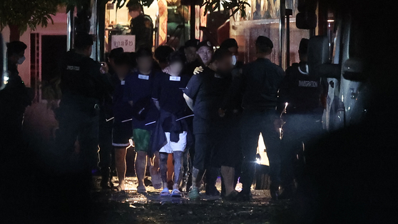 지난 17일(현지시간) 캄보디아 프놈펜에 위치한 이민청에서 테초국제공항으로 이동하는 버스에 오르는 구금 한국인들의 목 부근에 숫자가 매겨진 종이가 붙어있다. 연합뉴스
