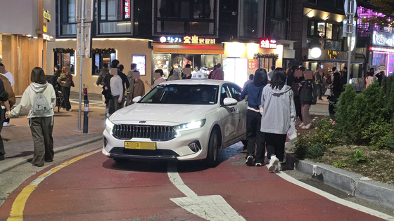 31일 서울 마포구 홍익대 앞 레드로드 회전교차로에 택시가 들어서고 있다. 이날 홍대 앞 도로 일부는 별다른 통제 없이 차도를 통행하는 시민과 차량이 계속해서 뒤섞였다. 김창용 기자