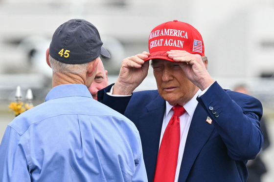 도널드 트럼프 미국 대통령이 지난 2월 16일(현지시간) 공화당의 릭 스콧 플로리다 주 상원의원과 대화하며 ″Make America Great Again″ 이라고 적힌 모자를 쓰고 있다. AFP=연합뉴스
