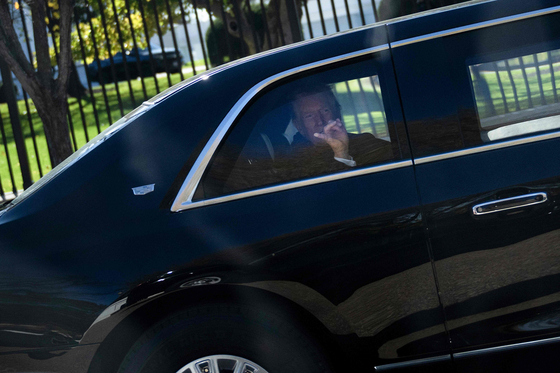 도널드 트럼프 미국 대통령이 11일(현지시간) 워싱턴 백악관을 떠나 재향군인의 날 기념식이 열리는 알링턴 국립묘지로 이동하는 동안 방탄 유리가 장착된 전용차 밖을 향해 손짓하고 있다. AFP=연합뉴스