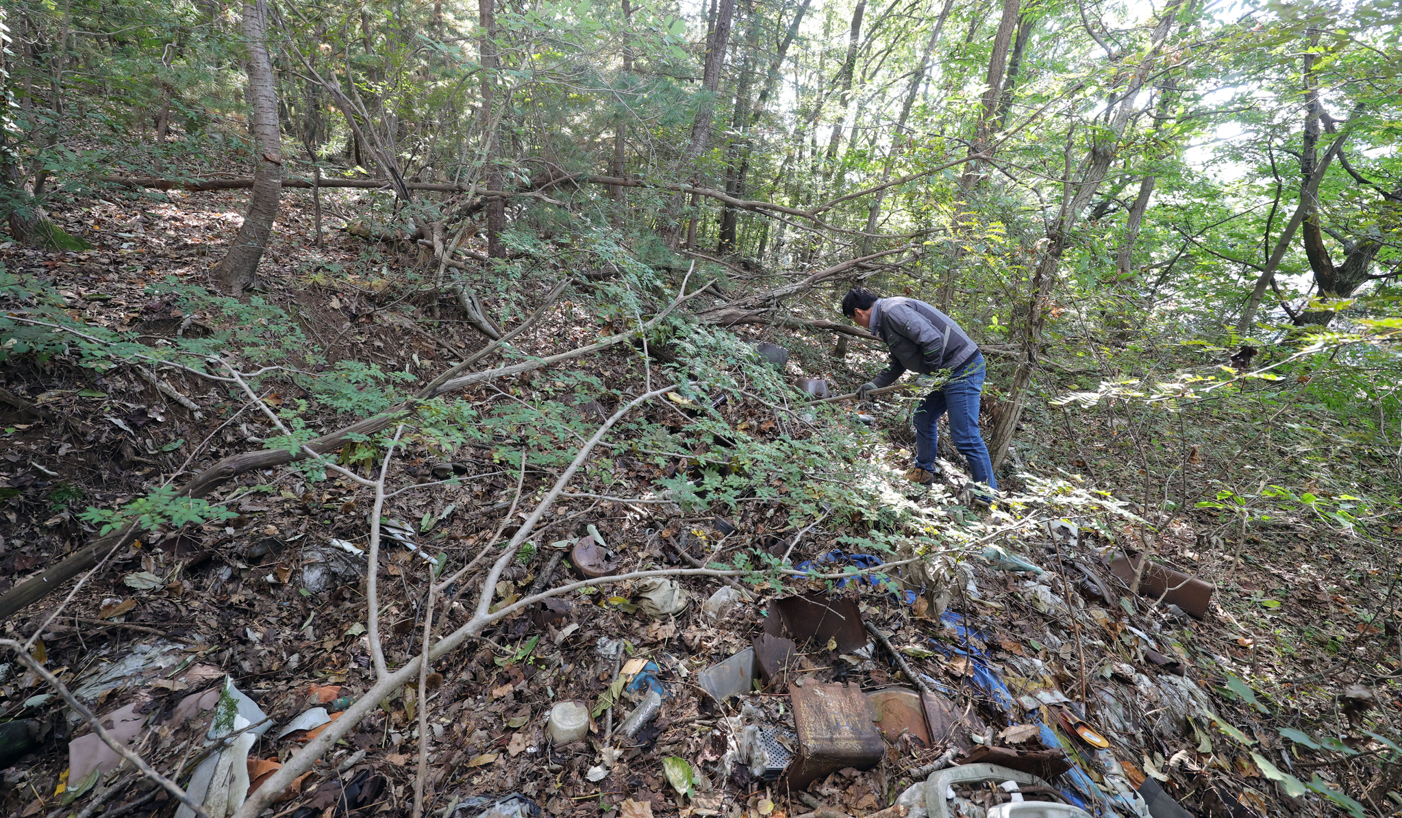 이이교 관장이 지난달 23일 석모도의 한 폐가 뒷산 쓰레기 무덤을 파헤치고 있다. 강정현 기자