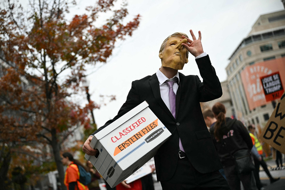 15일(현지시간) 워싱턴 DC 백악관 앞에서 한 시위자가 피노키오 코가 달린 도널드 트럼프 미국 대통령 마스크를 쓰고 '기밀 엡스타인 파일'이라고 적힌 상자를 들고 있다. AFP=연합뉴스