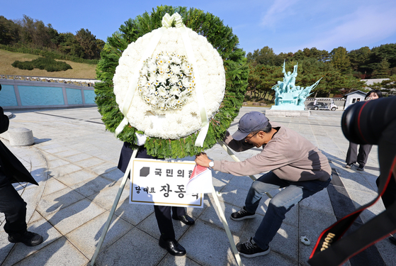 지난 6일 오후 광주 북구 국립5·18민주묘지에서 시민단체 한 회원이 장동혁 국민의힘 대표의 참배를 반대하며 추모 화환을 치우고 있다. 이날 참배 시도 과정에서 장 대표 지지자들과 시민단체 회원들 사이에서 서로 밀치거나 고성이 오가는 등 충돌이 빚어졌다. 연합뉴스