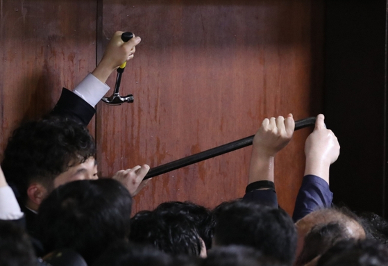 더불어민주당 의원과 보좌관들이 패스트트랙 사건 당시 여야4당의 수사권조정법안을 제출하기 위해 자유한국당 당직자들이 점거하는 국회 의안과에 '도구'를 사용해 진입 시도하고 있다. 연합뉴스