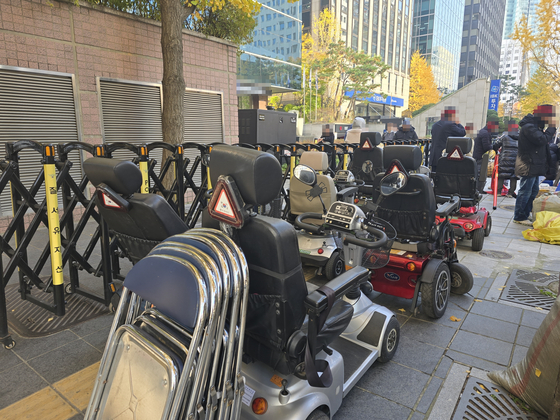 한 장애인 단체가 지난 20일 오전 서울 여의도의 한 증권사 앞에서 약정 기부금을 내놓으라며 버스와 확성기 등을 동원해 해당 증권사에 재직 중인 임원을 규탄하는 집회를 하고 있다. 사진은 증권사 앞 인도에 세워 둔 휠체어 6대. 손성배 기자