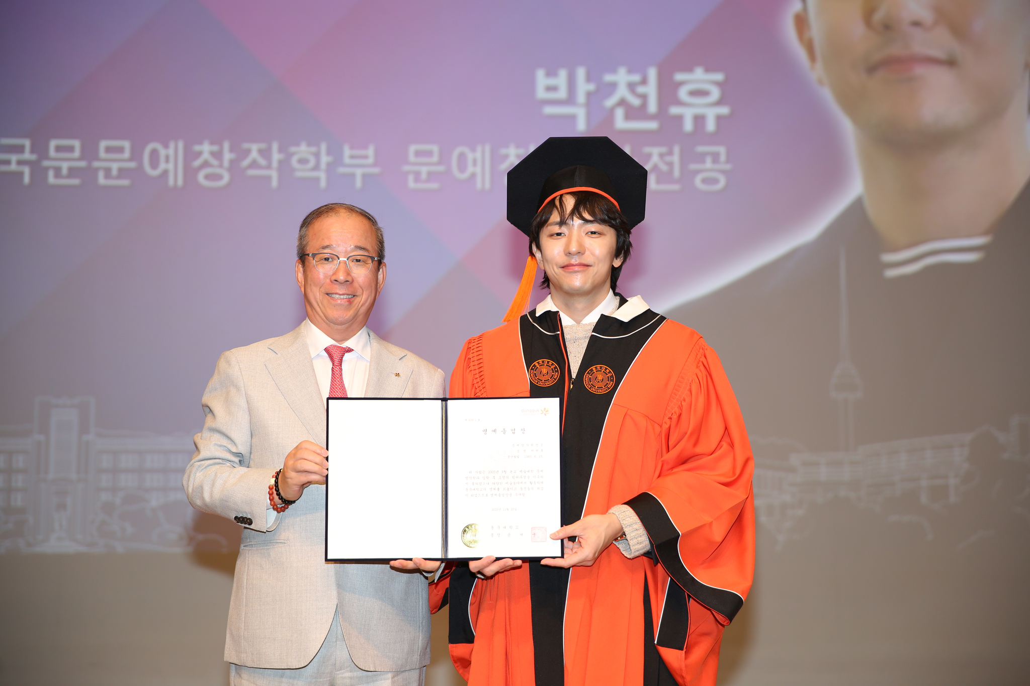 윤재웅 동국대 총장(왼쪽)이 박천휴 동문(오른쪽)에게 명예졸업장을 수여하고 기념사진을 촬영하고 있다.