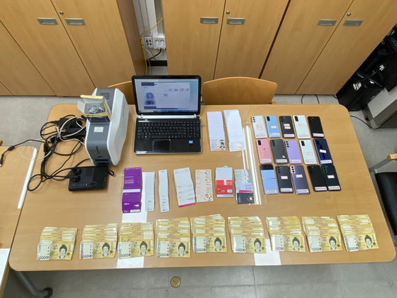 경찰이 스미싱 조직으로부터 압수한 휴대전화 공기계와 위조 신분증, 범죄 수익금. 사진 서울경찰청