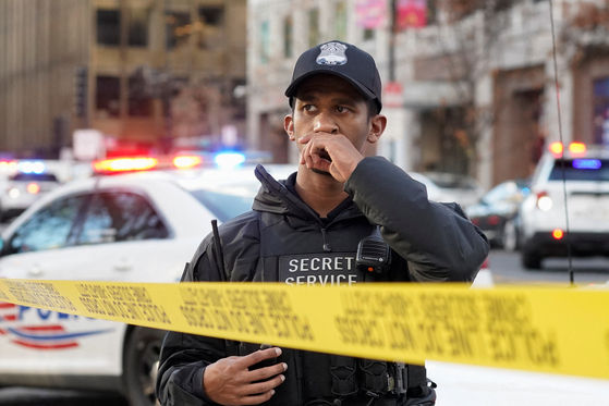 현지시간 26일 미국 워싱턴 백악관 인근에서 2명의 주방위군 대원이 총격을 받은 후, 미국 비밀경호국 요원이 노란색 폴리스라인 뒤에서 경계를 서고 있다. 로이터=연합뉴스