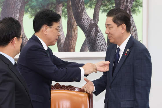 김병기 더불어민주당 원내대표와 송언석 국민의힘 원내대표가 28일 서울 여의도 국회에서 법인세율과 교육세 인상 문제를 두고 막판 협상을 위해 회동하고 있다.   취재진의 카메라 앞에 서기 전 송 원내대표가 김 원내대표의 옷깃에 붙은 먼지를 떼어주고 있다. 연합뉴스