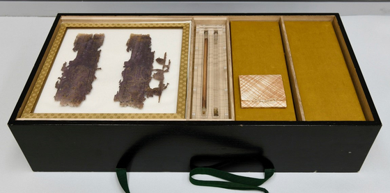 755년 완성한 '신라백지묵서 대방광불화엄경'의 보관 모습. 그림이 있는 표지는 아크릴 케이스에 넣고, 사경 전체는 옻칠한 오동나무 상자에 담았다. 가운데 막대는 각각 14m, 20m 두루마리를 고정한 나무 심과 장식. 사진 리움미술관