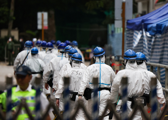  3일(현지시간) 홍콩 타이포의 왕푹코트 공공주택 단지에서 치명적 화재가 발생한 뒤, 개인보호장비(PPE)를 착용한 경찰관들이 건물 인근을 지나고 있다. 로이터=연합뉴스