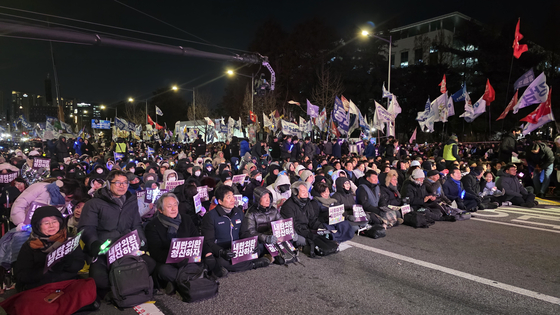비상행동 주최 집회에 참가한 시민들이 국회대로 바닥에 앉아 있다. 김창용 기자