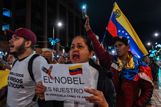 6일 콜롬비아 보고타에서 열린 마차도 지지 집회에서 한 여성이 베네수엘라 국기가 그려진 팻말을 들고 있다. AFP=연합뉴스