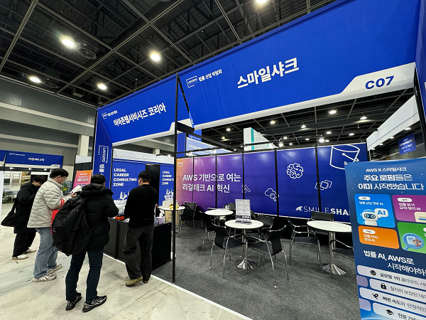 대한민국 법률산업 박람회 2025 스마일샤크 x AWS 공동 부스에서 스마일샤크 직원이 방문객에게 AI 도입 서비스를 소개하고 있다. (사진 제공=스마일샤크)