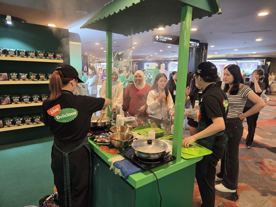 지난 11일(현지시간) 말레이시아 쿠알라룸푸르 인근 선웨이피라미드 컨벤션센터에서 열린 '한류박람회'에서 현지 방문객이 K푸드를 맛보고 있다. 김기환 기자