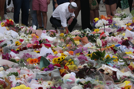16일(현지시간) 총격 사건이 벌어진 시드니 본다이 파빌리온 외부의 추모 장소에 한 유대인 인사가 꽃을 놓고 있다. AFP=연합뉴스