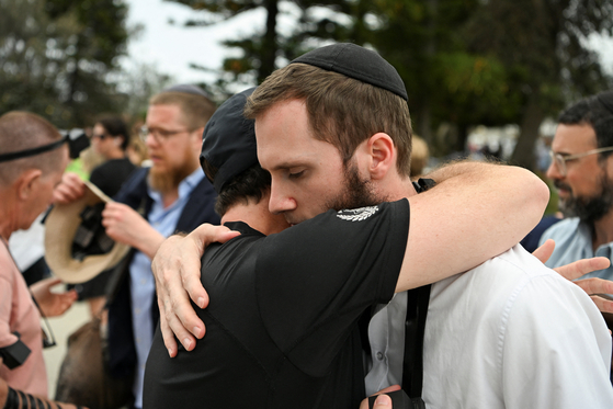 15일(현지시간) 호주 시드니 본다이 해변에서 열린 유대교 명절 행사 도중 총격 사건이 발생한 뒤, 인근 본다이 파빌리온 주변에서 사람들이 슬픔을 나누고 있다. 로이터=연합뉴스