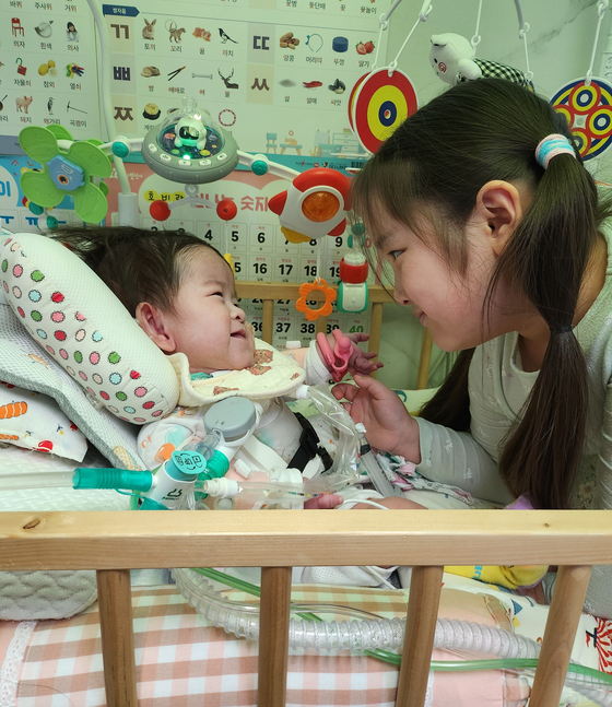  심장이소증을 안고 태어났지만, 치료 끝에 건강하게 성장한 아기 서린이와 언니가 마주보며 웃고 있다. 서울아산병원