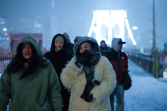 26일(현지시간) 미국 뉴욕에서 눈이 내리는 가운데 시민들이 브루클린 브리지를 건너고 있다. 로이터=연합뉴스