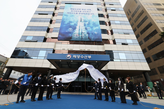 이재명 대통령이 23일 부산 동구 수정동 해양수산부 임시청사에서 열린 해수부 현판 제막식에서 참석자들과 가림천을 걷어내고 있다. [대통령실사진기자단=중앙일보 전민규 기자] 2025.12.23.