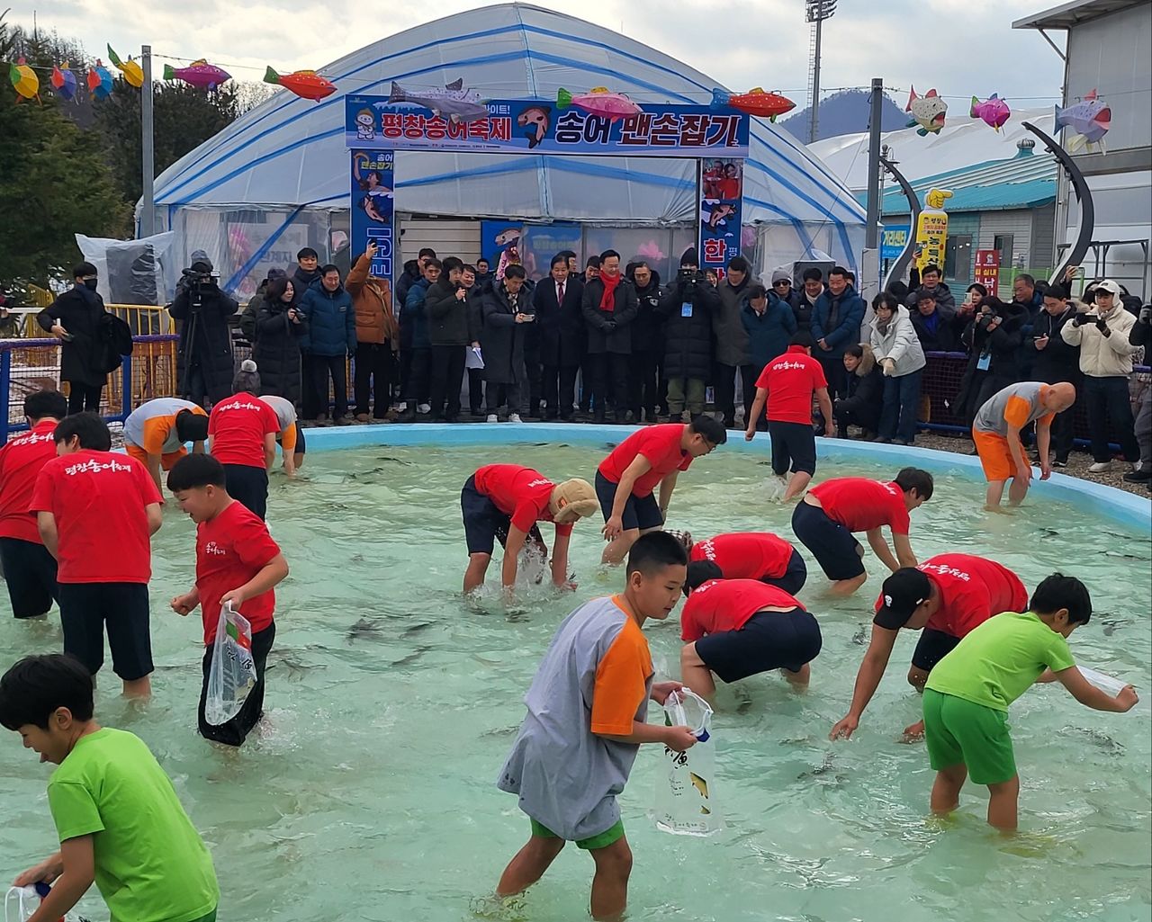 지난 9일 강원 평창군 진부면 오대천 일원에서 개막한 '평창송어축제'를 찾은 관광객들이 맨손으로 송어를 잡는 프로그램에 참여하고 있는 모습. [뉴스1]