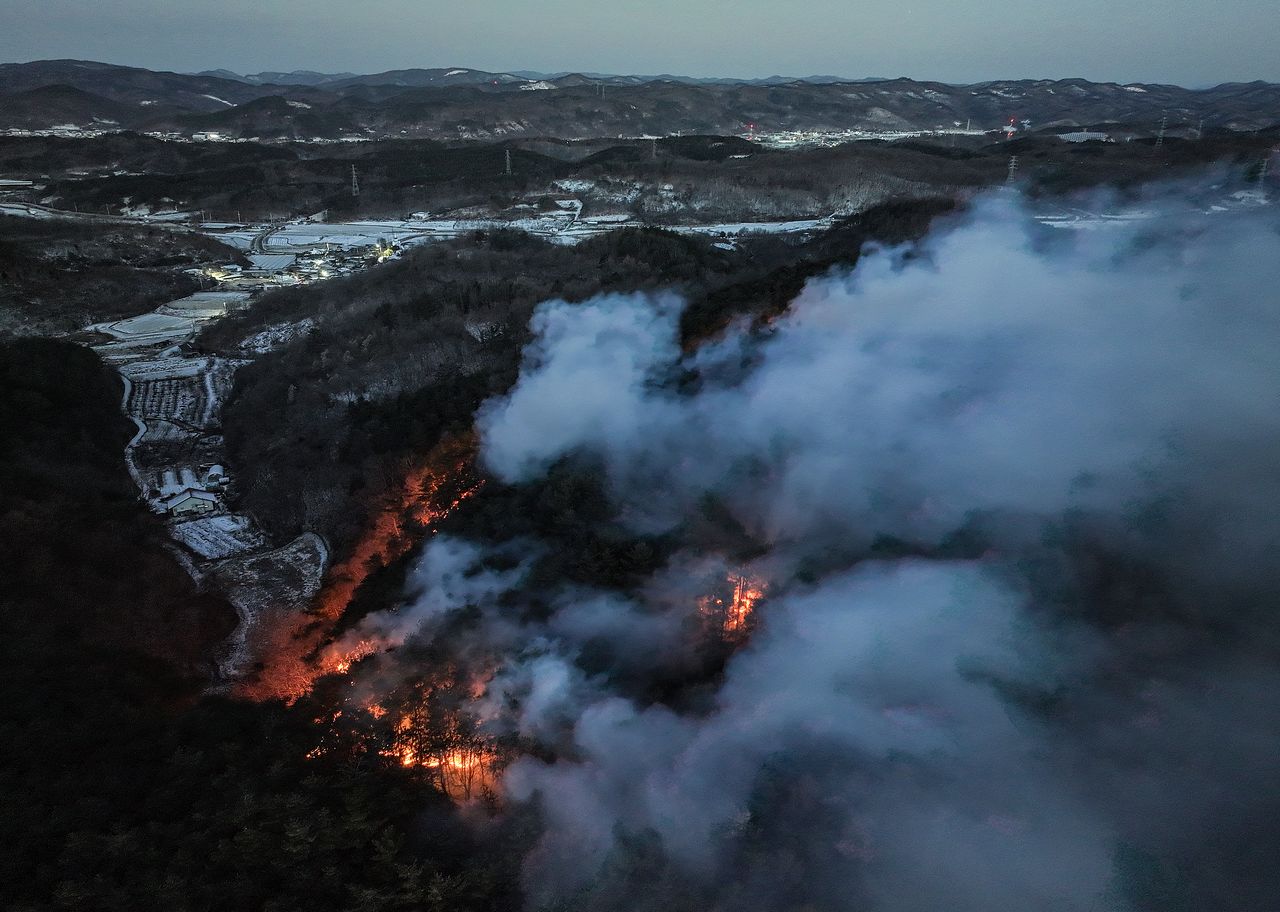 11일 오전 경북 의성군 의성읍 일대에 눈이 쌓인 가운데 인근 야산에서 전날 발생한 산불의 잔불이 남아 타오르고 있다. 연합뉴스