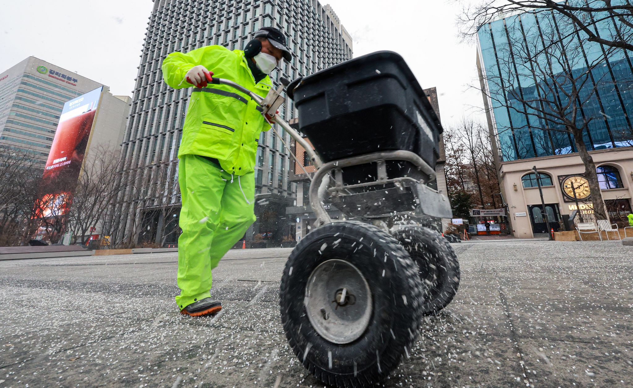 12일 서울 광화문광장에서 관계자가 인도 결빙을 막기 위해 염화칼슘을 살포하고 있다. 뉴스1