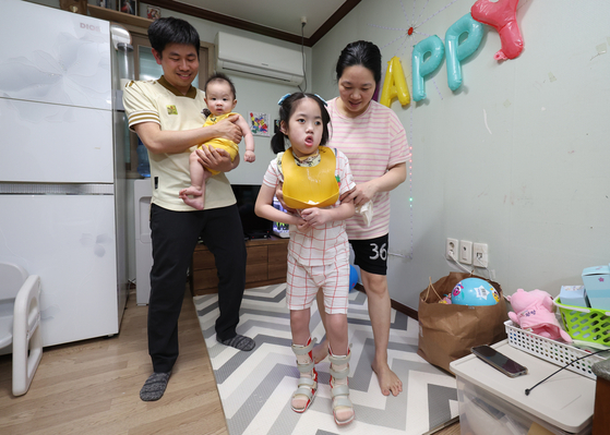 판 반 투언(39)과 딸 장미(9)의 가족의 모습. 양쪽 발목에 보조기를 찬 장미가 엄마에게 의지해 걷고 있다. 송봉근 기자