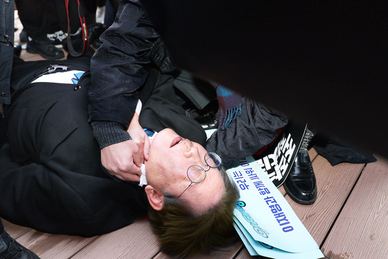 2024년 1월 2일 이재명 당시 더불어민주당 대표가 부산 가덕도 신공항 부지를 둘러본 후 기자들과 문답을 진행하던 중 왼쪽 목 부위에 습격을 당해 피를 흘린 채 쓰러져 있다. 연합뉴스