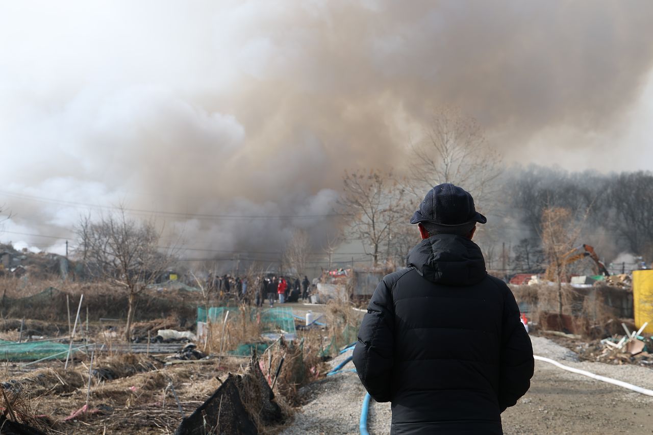 16일 서울 강남구 개포동 구룡마을 4지구 화재현장 소방 통제선 밖에서 주민이 현장을 지켜보고 있다. 연합뉴스
