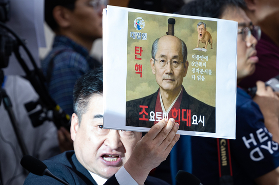 최혁진 무소속 의원이 지난해 10월 13일 서울 여의도 국회에서 열린 법제사법위원회의 대법원 등에 대한 국정감사에서 조희대 대법원장에게 질의하며 손팻말을 들어보이고 있다. 뉴스1