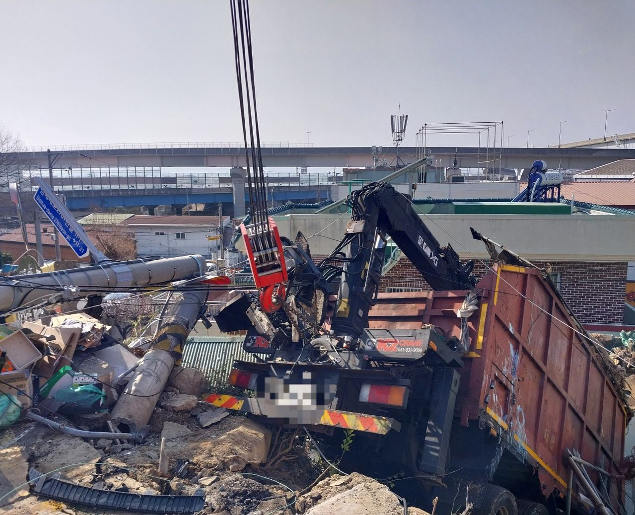 18일 오전 11시 17분쯤 경남 김해시 불암동 한 언덕 내리막길에서 60대 A씨가 몰던 화물차가 전신주를 들이받고 주택가로 떨어지는 사고가 발생했다. 이 사고로 내리막길에 주차돼 있던 차량 1대와 전신주 1대, 난간 아래에 있던 주택 1채 일부가 파손됐다. 사진 경남소방본부