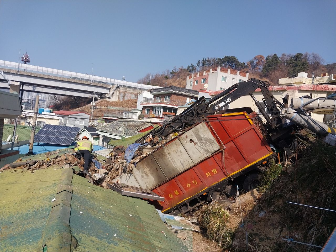 18일 오전 11시 17분쯤 경남 김해시 불암동 한 언덕 내리막길에서 60대 A씨가 몰던 화물차가 전신주를 들이받고 주택가로 떨어지는 사고가 발생했다. 이 사고로 내리막길에 주차돼 있던 차량 1대와 전신주 1대, 난간 아래에 있던 주택 1채 일부가 파손됐다. 사진 경남소방본부