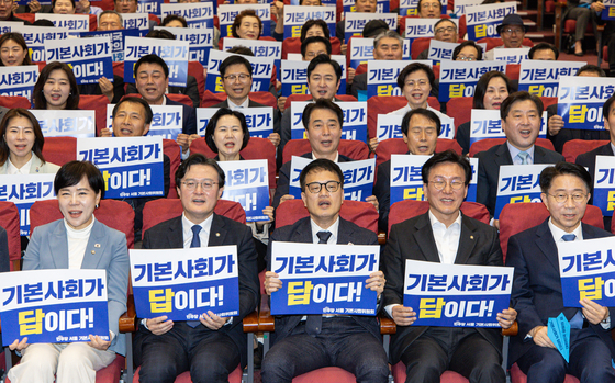 지난해 4월 11일 오후 서울 여의도 국회 의원회관에서 열린 민주당 서울 기본사회위원회 발대식에서 참가자들이 피켓을 들고 구호를 외치고 있다. 뉴스1