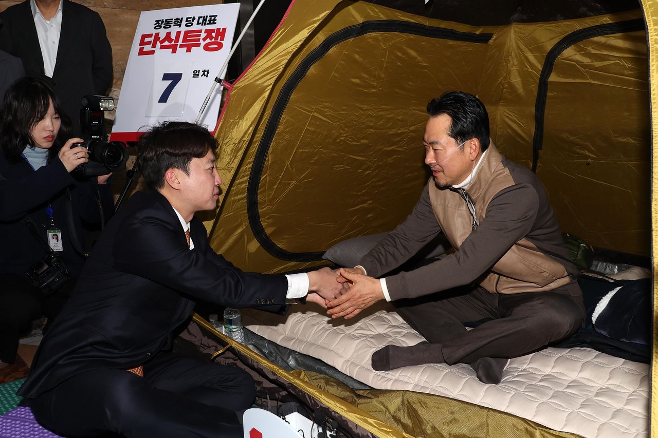 장동혁 국민의힘 대표가 21일 오전 서울 여의도 국회 로텐더홀에서 '민주당의 공천 뇌물, 통일교 게이트 특검 수용'을 촉구하며 단식농성 중 이준석 개혁신당 대표와 대화를 하며 손을 잡고 있다. 뉴시스