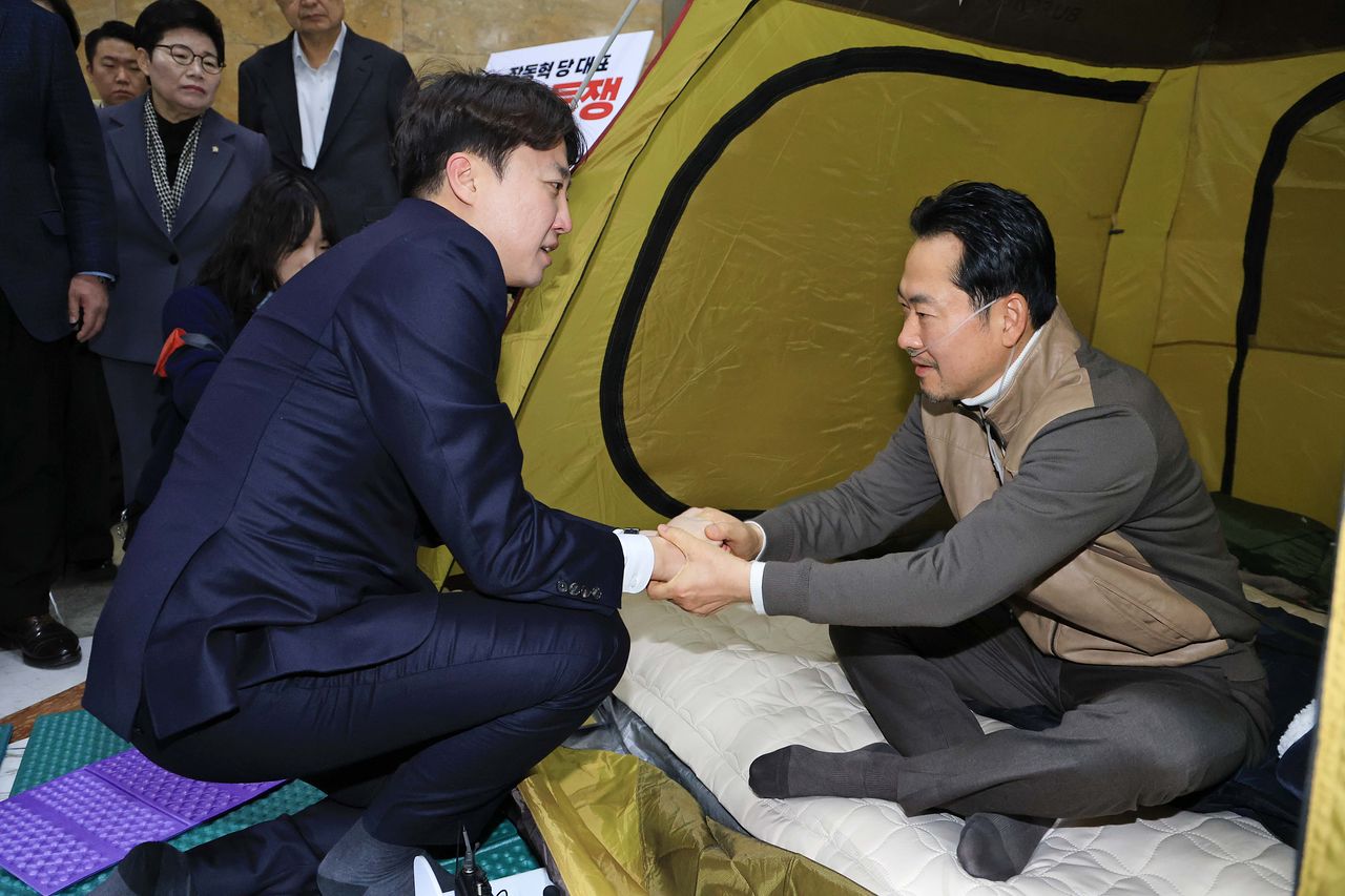 이준석 개혁신당 대표(왼쪽)가 21일 국회 로텐더홀 농성장을 찾아 단식 중인 장동혁 국민의힘 대표에게 “힘내십시오”라며 인사하고 있다. [연합뉴스]