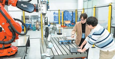 한국공학대학교 김효영 교수(왼쪽)가 AI 팩토리 연구센터에서 가공로봇과 협동로봇을 활용한 AI 기반 제조·공정 실증 기술을 연구원과 함께 점검하고 있다. [사진 한국공학대학교]