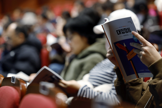 지난해 11월 서울 영등포구 영등포아트홀에서 열린 2026학년도 대입 정시 지원전략 설명회를 찾은 학부모들이 진학사의 대입 정시 합격전략가이드를 보고 있다. 뉴스1