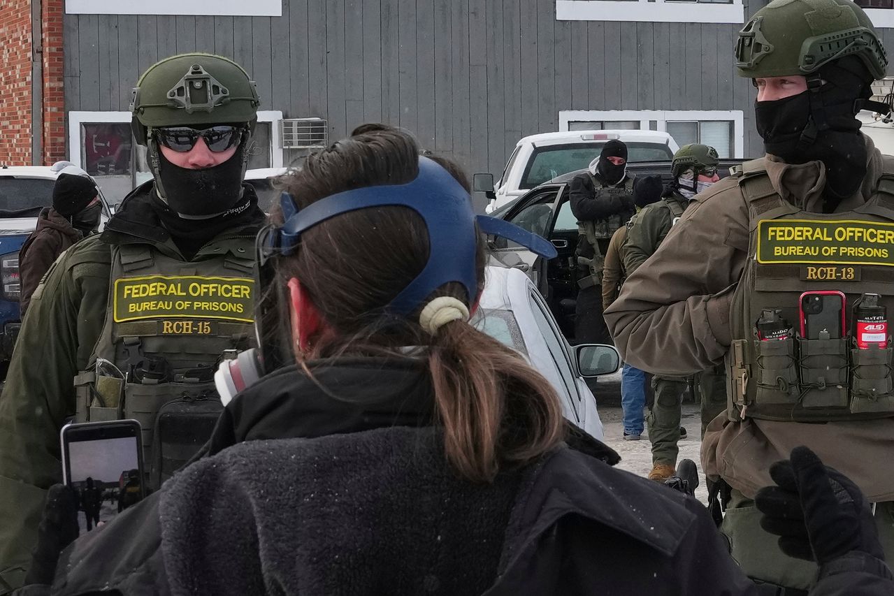  25일(현지시간) 미국 미네소타주 미니애폴리스의 한 아파트 인근에서 연방 요원들이 현장조사를 하는 가운데 시위대 1명이 이들 앞에 서 있다. AP=연합뉴스