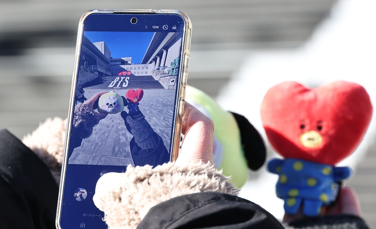 지난 22일 서울 종로구 세종문화회관 계단에서 일본인 관광객들이 오는 3월 3년 9개월 만에 '완전체'로 돌아오는 그룹 방탄소년단(BTS)의 컴백을 알리는 홍보물을 배경으로 기념사진을 촬영하고 있다. 사진 연합뉴스