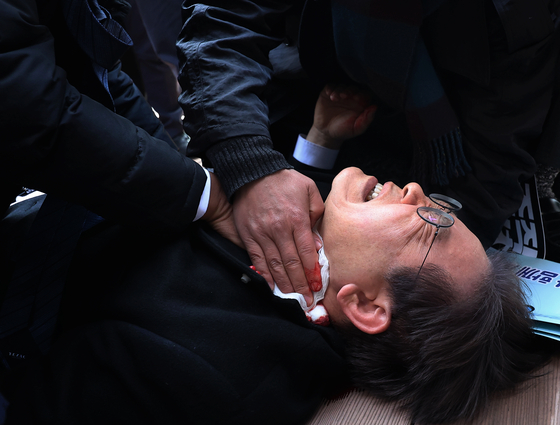 이재명 대통령이 더불어민주당 대표였던 2024년 1월 2일 제22대 총선을 앞두고 부산 가덕도 신공항 부지를 둘러본 후 기자들과 문답을 진행하던 중 왼쪽 목 부위를 습격당해 피를 흘린 채 쓰러진 모습. 연합뉴스