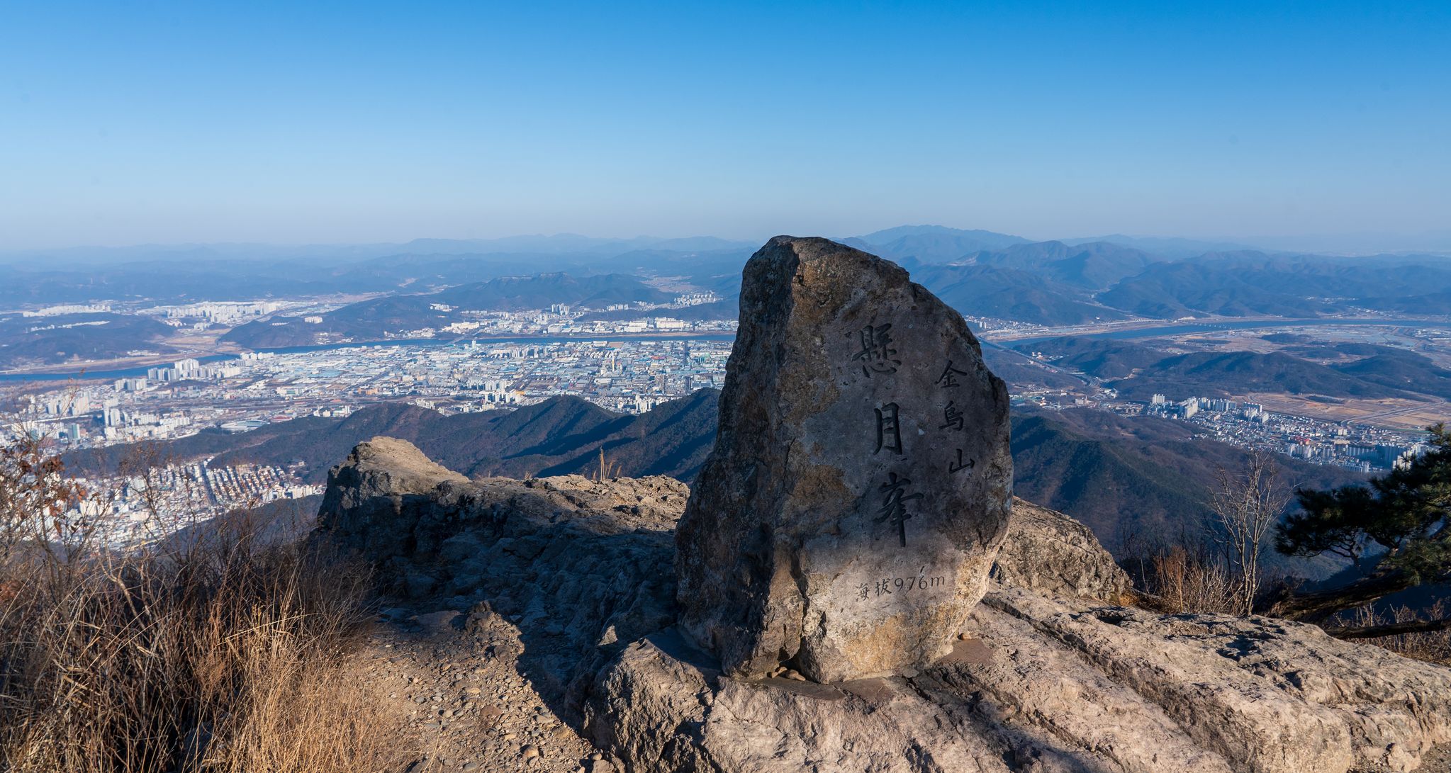 금오산 현월봉. 정상석 너머로 구미 산업단지가 보인다. 현월봉 아래의 벼랑 한편에 약사암이 있다. 백종현 기자