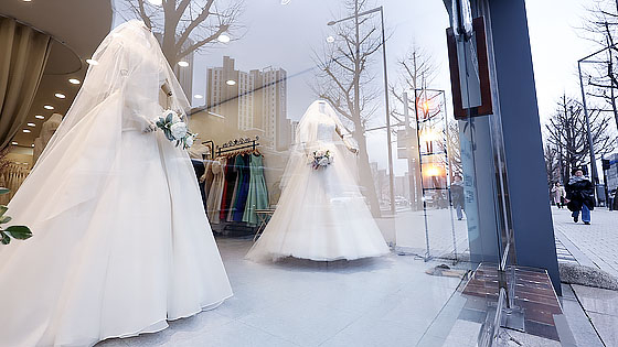 서울 마포구 아현동 웨딩거리에서 한 시민이 웨딩드레스 앞을 지나고 있다. 연합뉴스