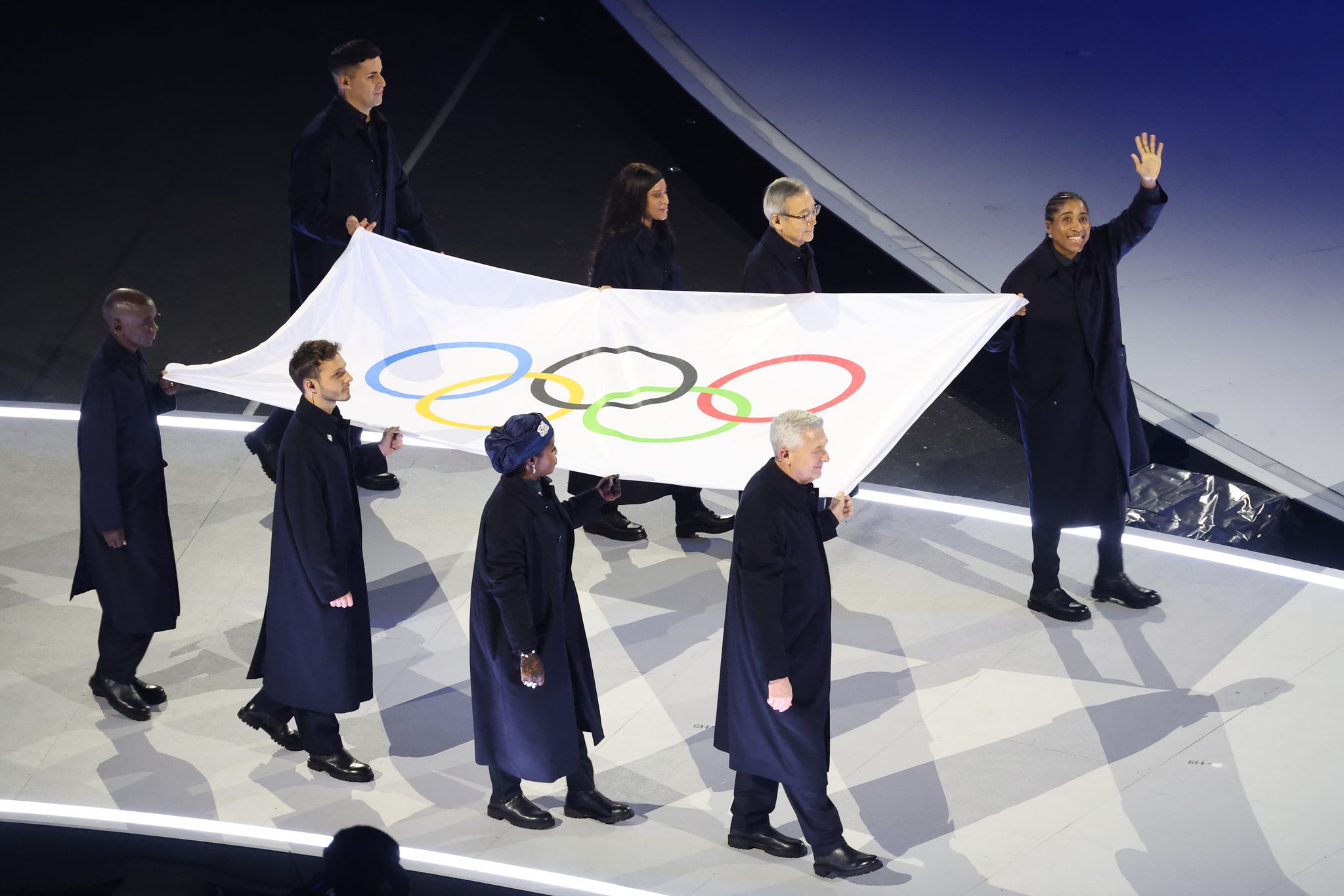 2026 동계올림픽 개회식에서 기수들이 오륜기를 들고 입장하고 있다.    이날 '마라톤 전설' 엘리우드 킵초게(케냐), 난민팀 역대 최초의 올림픽 메달리스트 신디 은감바, 인도주의 활동을 펼친 필리포 그란디, 니콜로 고보니(이상 이탈리아), 마리암 부카 하산(니이지리아), 올림픽 6개 메달을 딴 체조 선수 레베카 안드라드(브라질), 핵 군축 활동을 펼친 아키바 다다토시(일본) 전 히로시마 시장이 '통가 근육맨'타우파토푸아와 함께 오륜기 기수로 입장했다. 연합뉴스