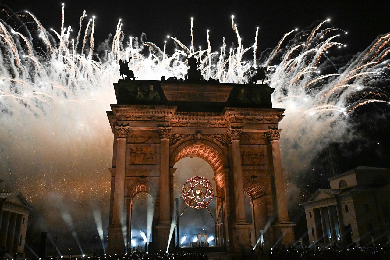 지난 6일(현지시간) 열린 밀라노·코르티나 2026 동계올림픽 개막식에서 마르코 발리치가 디자인한 ‘평화의 아치’(아르코 델라 파체·Arco della Pace)의 성화대에 불이 타오르는 가운데, 뒤편으로 불꽃놀이가 펼쳐지고 있다. AFP=연합뉴스